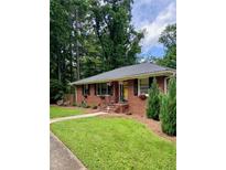 Charming brick home featuring a well-manicured lawn, tidy landscaping, and a welcoming yellow front door at 406 S Hillcrest Sw Dr, Marietta, GA 30064