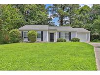 Charming single-story home featuring manicured lawn, mature trees, and a one car garage at 1234 Wellhouse Walk, Stone Mountain, GA 30088