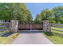 View of the gated entrance to the property, featuring stone pillars and a black metal gate at 664 Johnson Rd, Oxford, GA 30054