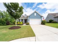 Charming blue home featuring a manicured lawn, colorful shrubs, and a classic two-car garage at 7430 Ramsgate Ct, Cumming, GA 30040