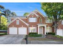 Traditional brick home with a two-car garage, mature landscaping, and a well-maintained front yard at 401 Wellwood Way, Roswell, GA 30075