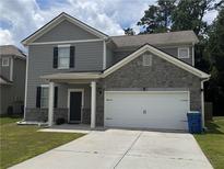Two-story home featuring a two-car garage, gray siding and stone accents, and a well-maintained lawn at 7637 Rudder Cir, Fairburn, GA 30213