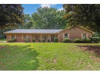Charming brick home featuring a well-manicured lawn and mature trees providing shade at 326 Acaro Ct, Ellenwood, GA 30294