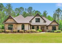 Beautiful single-Gathering home featuring a manicured lawn and a charming stone and siding exterior at 35 Cornish Creek Ln, Covington, GA 30014