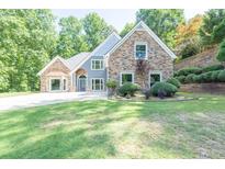 Charming home with stone and blue siding, complemented by a well-manicured lawn and landscaped hillside at 3365 Sweetwater Dr, Cumming, GA 30041