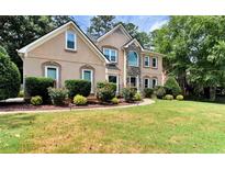 Charming two-story home featuring a manicured lawn, mature trees, and stone accents at 4335 Burgomeister Pl, Snellville, GA 30039