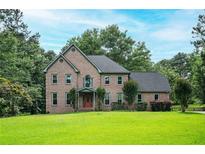 Charming two-story brick home with a well-manicured lawn and mature trees at 13789 Woolsey Rd, Hampton, GA 30228