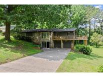 Charming home featuring a stone facade, two-car garage, and a spacious deck surrounded by lush greenery at 2600 Sandpiper Dr, Tucker, GA 30084