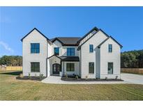 Stunning two-story home featuring black trim, white painted brick and manicured lawn on a sunny day at 0 Thompson Mill Rd, Buford, GA 30519