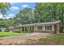 Charming ranch-style home with a brick facade, covered porch, mature trees, and a spacious driveway at 1724 Rhonda Ln, Stone Mountain, GA 30087