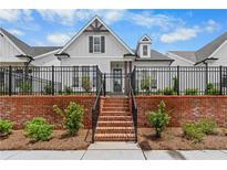 Charming home with a brick retaining wall, a black fence, and inviting steps leading to the entrance at 513 Godfrey Dr, Cumming, GA 30040