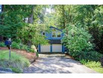 Charming blue home featuring a two-car garage surrounded by lush greenery and a well-manicured lawn at 3531 Evans Ridge Dr, Atlanta, GA 30341