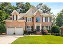Beautiful two-story brick home with a well-manicured lawn, flowering shrubs, and a two-car garage at 6211 Traymore Se Trce, Smyrna, GA 30082