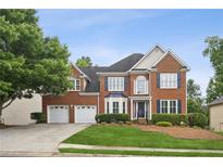 Beautiful two-story brick home featuring a two-car garage and lush green landscaping at 130 White Sands Ct, Suwanee, GA 30024