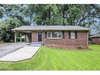 Charming brick home with a covered parking area and well-maintained front lawn at 1856 Austell Sw Cir, Marietta, GA 30060