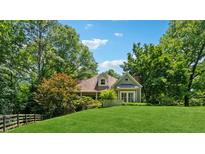 Charming home with a lush green lawn, mature trees, and a quaint picket fence at 1042 Bailey Rd, Woodstock, GA 30188