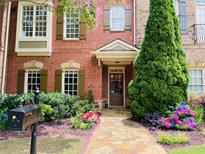 Charming brick townhome featuring a stone walkway, lush landscaping, and manicured lawn at 578 Parkside Village Nw Way, Marietta, GA 30060