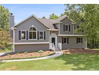 Charming two-story home with a manicured lawn, gray siding, black shutters, and a stone accented entryway at 1400 Land Rd, Canton, GA 30114