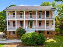 Two-story pink home featuring double front porches, white columns, and lush landscaping at 3348 Summit Turf Ln, Snellville, GA 30078