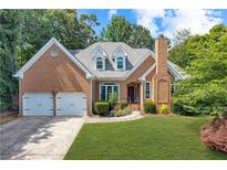 Charming brick home featuring a two-car garage, well-manicured lawn, and classic architectural details at 10880 Windham Way, Alpharetta, GA 30022