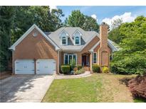 Charming brick home featuring a two-car garage, manicured lawn, and mature landscaping at 10880 Windham Way, Alpharetta, GA 30022