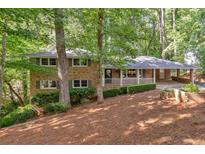 Charming brick home with covered porch, carport, and beautifully landscaped front yard with mature trees at 620 Amberidge Trl, Atlanta, GA 30328
