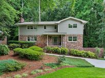 Charming home with a landscaped front yard, brick accents, and surrounded by lush greenery and mature trees at 2973 Payton Ne Rd, Atlanta, GA 30345