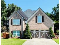 Charming two-story brick home with a well-manicured lawn, two-car garage, and meticulous landscaping at 3560 Elinburg Dr, Buford, GA 30519