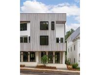 Modern townhouse showcasing striking wood siding, sleek black windows, and inviting glass-panel doors at 11560 Serenbe Ln, Chattahoochee Hills, GA 30268