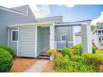 Inviting condo exterior features a covered porch, lush landscaping, and light-green siding at 325 Berry Ct, Villa Rica, GA 30180