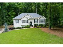Charming one-story home boasts a lush green lawn and beautiful landscaping, surrounded by mature trees at 5930 Shannon Drive Dr, Cumming, GA 30040