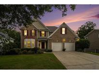 Charming brick home with manicured lawn, two-car garage, and lovely sunset in the background at 5925 Crescent Landing Dr, Cumming, GA 30028