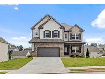 Beautiful two-story home featuring a brick and gray siding exterior with an attached two-car garage and a well-maintained lawn at 1494 Weeping Tree Cir, Auburn, GA 30548