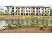 Townhome community featuring a pond, lush landscaping, and modern facades at 344 Olmstead Way # 32, Alpharetta, GA 30022