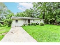 Front exterior of a single-story home surrounded by mature trees and a lush green lawn at 3133 Cottonwood Se Dr, Atlanta, GA 30316