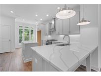 Modern kitchen features white cabinets, quartz countertops, stainless steel appliances, and a center island at 334 Olmstead Way # 37, Alpharetta, GA 30022