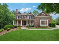Stunning brick home features a manicured lawn and inviting front porch with white columns at 245 River Laurel Way, Woodstock, GA 30188