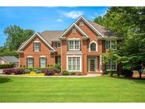 Beautiful two-story brick home with a lush green lawn, manicured landscaping and attractive curb appeal at 4075 Hickory Fairway Dr, Woodstock, GA 30188