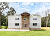 Two-story home with a stone facade, light gray exterior, covered entrance, and landscaped front yard at 2369 Mcafee Rd, Decatur, GA 30032