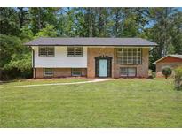 Charming brick home featuring a well-manicured lawn, classic architectural design, and a welcoming light blue front door at 3611 Radcliffe Blvd, Decatur, GA 30034