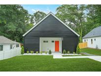 Charming exterior elevation of a modern home with black siding, a bright orange front door and a well manicured lawn at 587 Woods Nw Dr, Atlanta, GA 30318