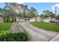Cozy home featuring a blend of siding and stone accents, complemented by a long driveway and manicured lawn at 1181 Mannbrook Dr, Stone Mountain, GA 30083