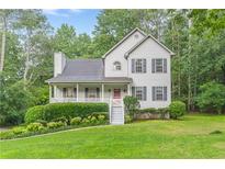 Charming two-story home with grey siding, shutters, a cozy front porch, and lush landscaping at 5609 Twin Oak Dr, Douglasville, GA 30135