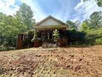 Charming brick home with overgrown vines and a front porch, set on a treed lot at 8872 Conners Rd, Villa Rica, GA 30180