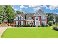 Beautiful brick home features manicured lawn, mature trees, and lovely landscaping at 189 Azalea Chase Dr, Suwanee, GA 30024