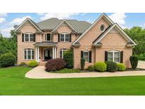 Traditional brick home featuring a well-manicured lawn, mature landscaping, and a welcoming entrance at 5755 Riley Rd, Cumming, GA 30028