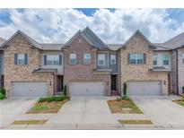 Charming townhome featuring a brick facade, attached garage, and well-manicured landscaping at 2005 Hamilton Creek Pkwy, Dacula, GA 30019