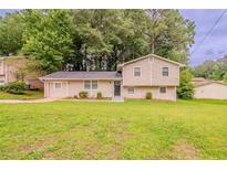 Charming two-story home with well-maintained lawn and inviting curb appeal nestled amongst mature trees at 2233 Cherokee Valley Dr, Lithonia, GA 30058