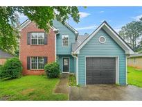 Charming two-story home with a brick facade and blue siding and a well-maintained lawn at 4753 Klondike Cv, Lithonia, GA 30038