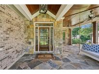 Inviting front porch with stone accents, a porch swing and ceiling fans at 1589 Trentwood Ne Pl, Brookhaven, GA 30319